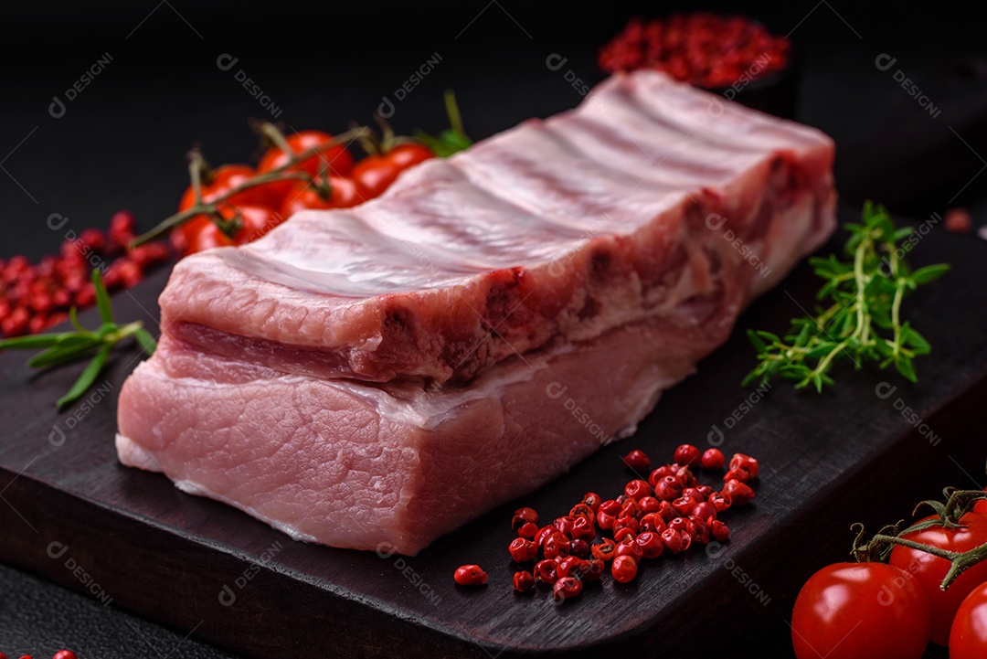 Costelas de porco cruas com sal, especiarias e ervas em fundo de concreto texturizado