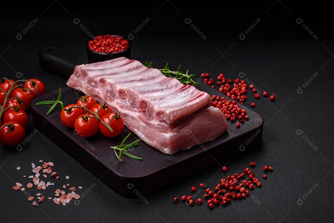 Costelas de porco cruas com sal, especiarias e ervas em fundo de concreto texturizado