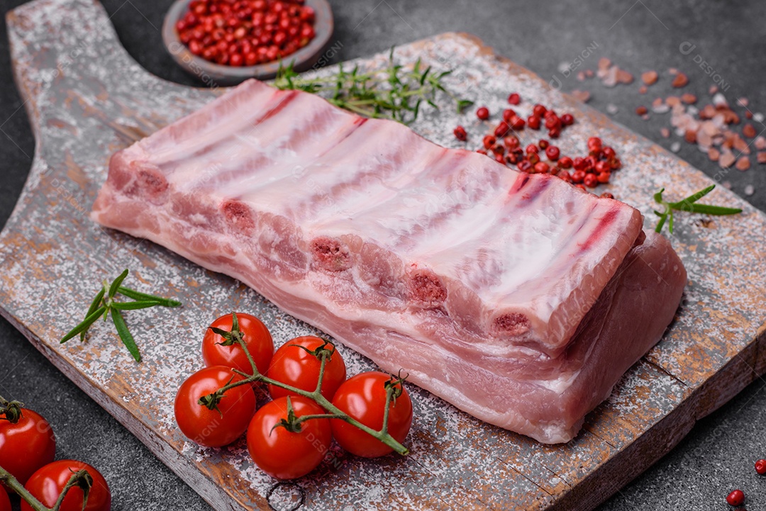 Costelas de porco cruas com sal, especiarias e ervas em fundo de concreto texturizado