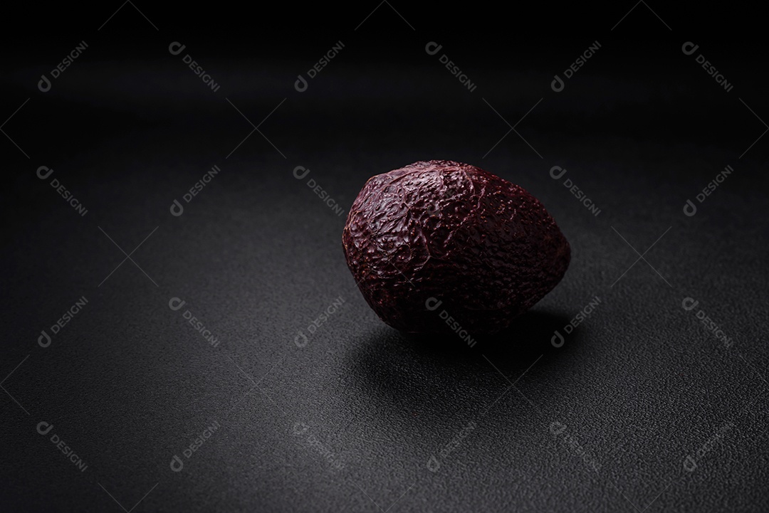 Abacate fresco, maduro e de cor marrom suave sobre um fundo escuro de concreto. Ingredientes culinários saudáveis