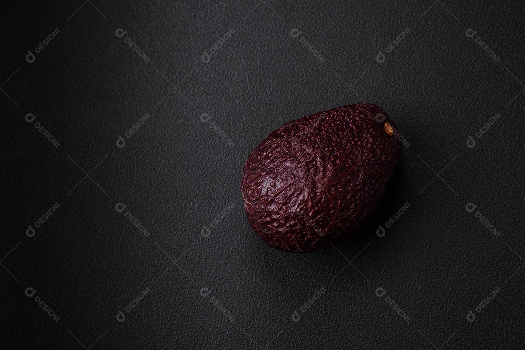 Abacate fresco, maduro e de cor marrom suave sobre um fundo escuro de concreto. Ingredientes culinários saudáveis