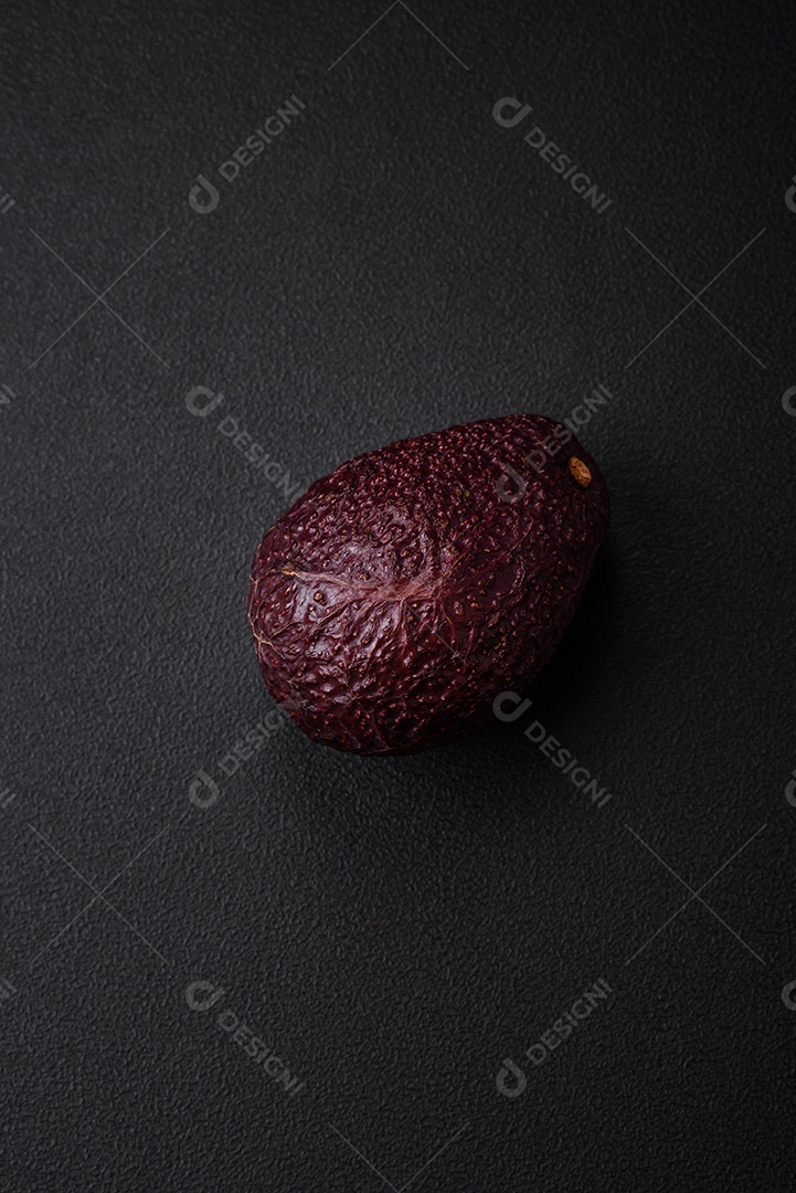 Abacate fresco, maduro e de cor marrom suave sobre um fundo escuro de concreto. Ingredientes culinários saudáveis