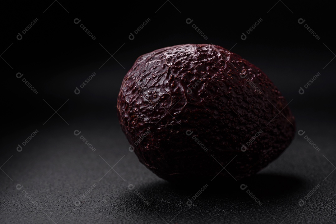 Abacate fresco, maduro e de cor marrom suave sobre um fundo escuro de concreto. Ingredientes culinários saudáveis