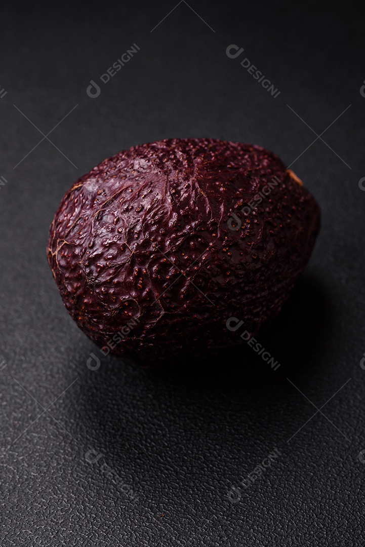 Abacate fresco, maduro e de cor marrom suave sobre um fundo escuro de concreto. Ingredientes culinários saudáveis