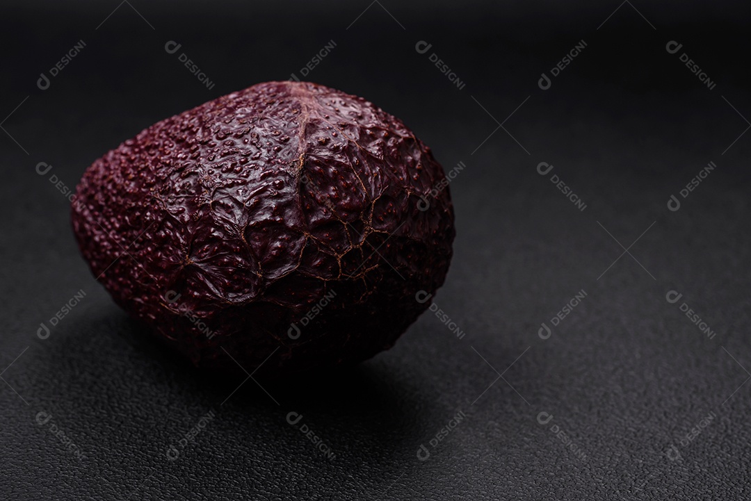 Abacate fresco, maduro e de cor marrom suave sobre um fundo escuro de concreto. Ingredientes culinários saudáveis