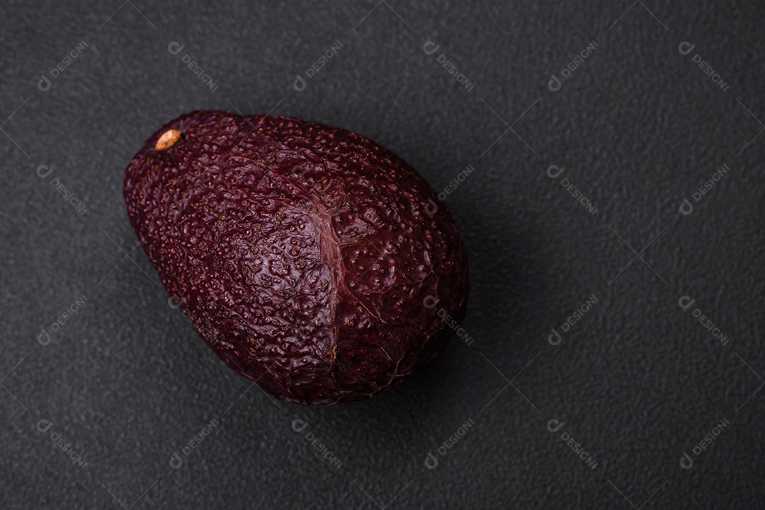 Abacate fresco, maduro e de cor marrom suave sobre um fundo escuro de concreto. Ingredientes culinários saudáveis