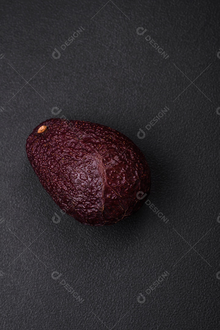 Abacate fresco, maduro e de cor marrom suave sobre um fundo escuro de concreto. Ingredientes culinários saudáveis