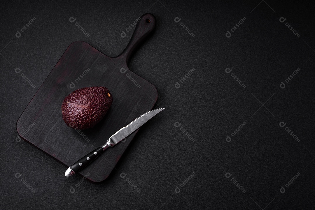 Abacate fresco, maduro e de cor marrom suave sobre um fundo escuro de concreto. Ingredientes culinários saudáveis