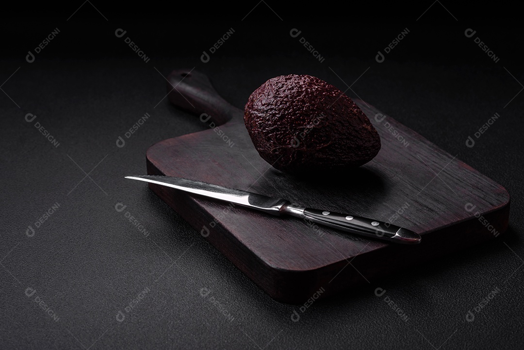 Abacate fresco, maduro e de cor marrom suave sobre um fundo escuro de concreto. Ingredientes culinários saudáveis