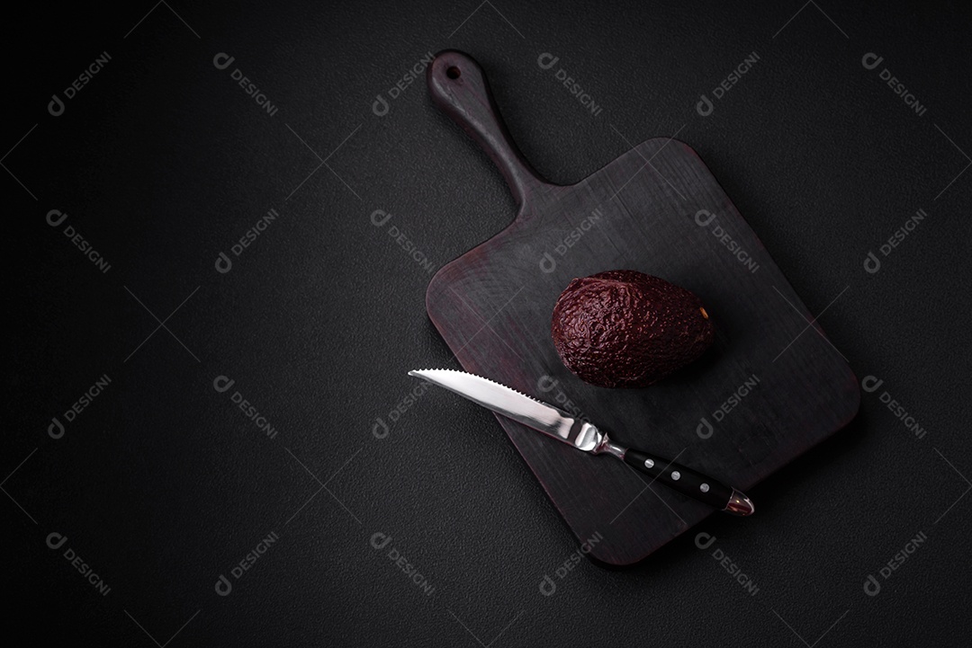 Abacate fresco, maduro e de cor marrom suave sobre um fundo escuro de concreto. Ingredientes culinários saudáveis