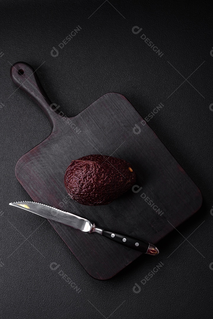 Abacate fresco, maduro e de cor marrom suave sobre um fundo escuro de concreto. Ingredientes culinários saudáveis