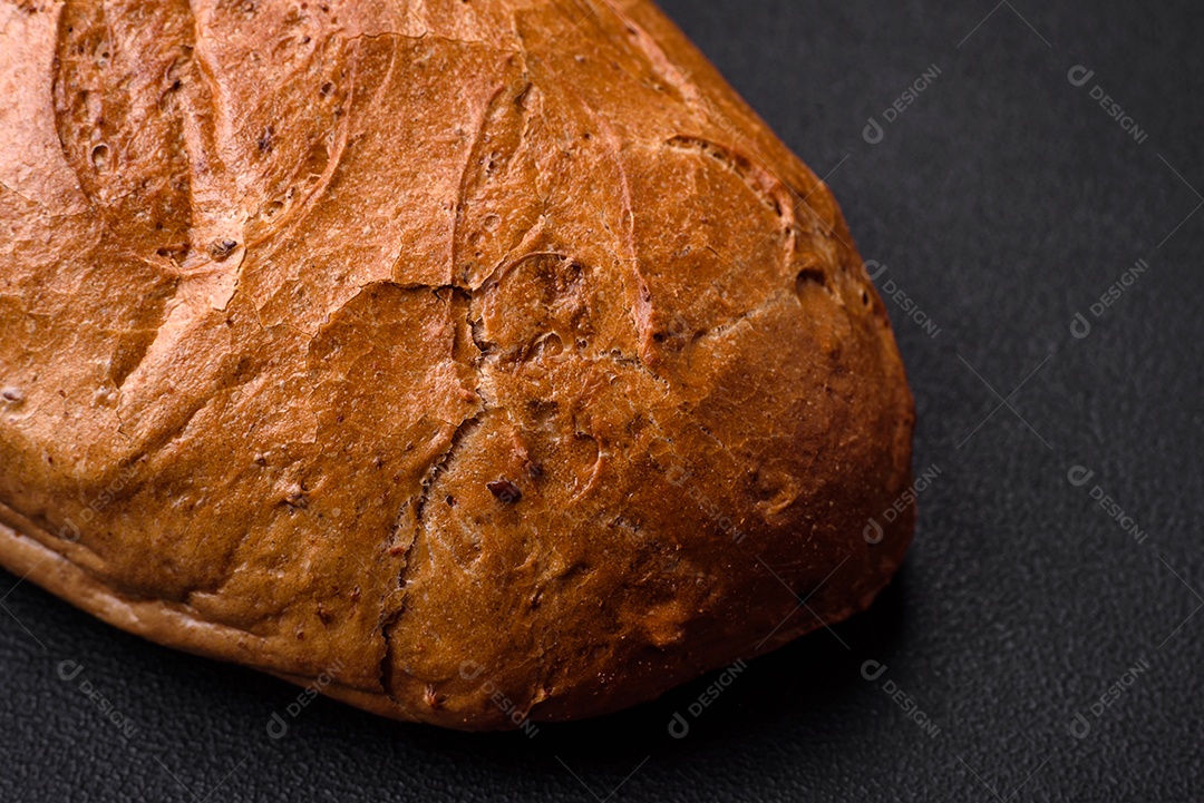 Delicioso pão branco fresco e crocante com grãos e sementes sobre um fundo escuro textural