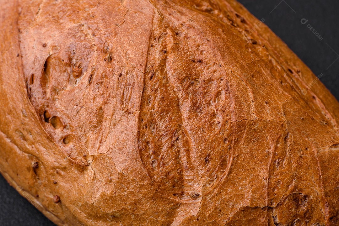 Delicioso pão branco fresco e crocante com grãos e sementes sobre um fundo escuro textural