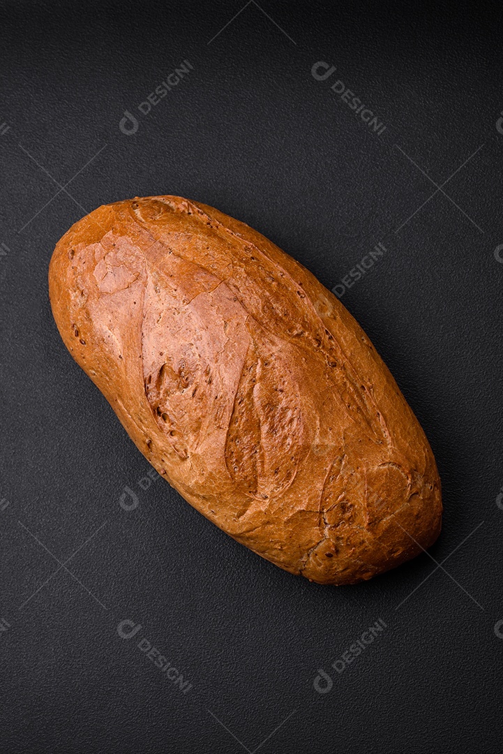 Delicioso pão branco fresco e crocante com grãos e sementes sobre um fundo escuro textural