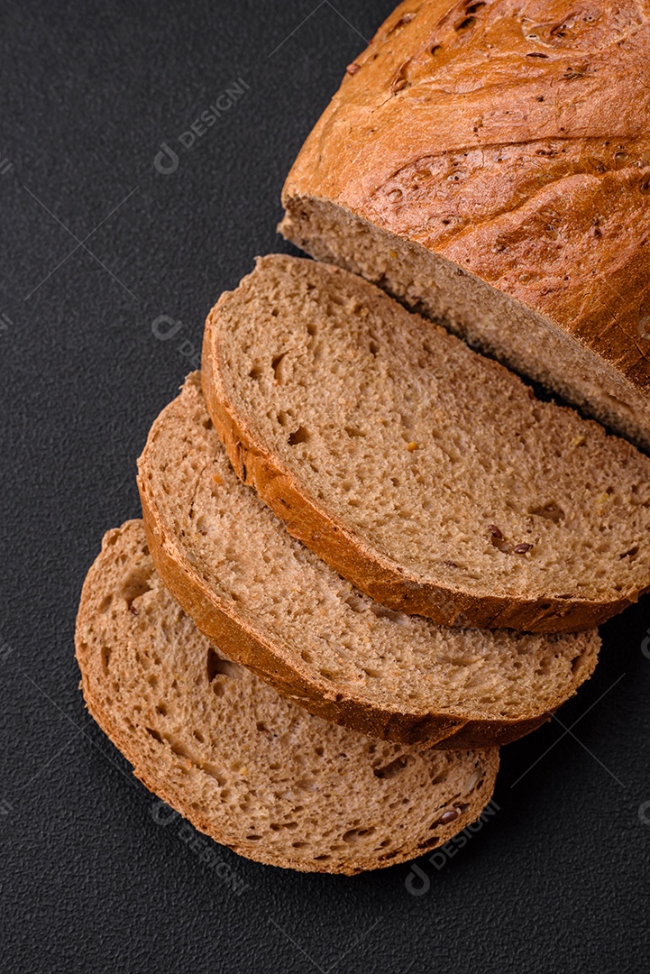 Delicioso pão branco fresco e crocante com grãos e sementes sobre um fundo escuro textural