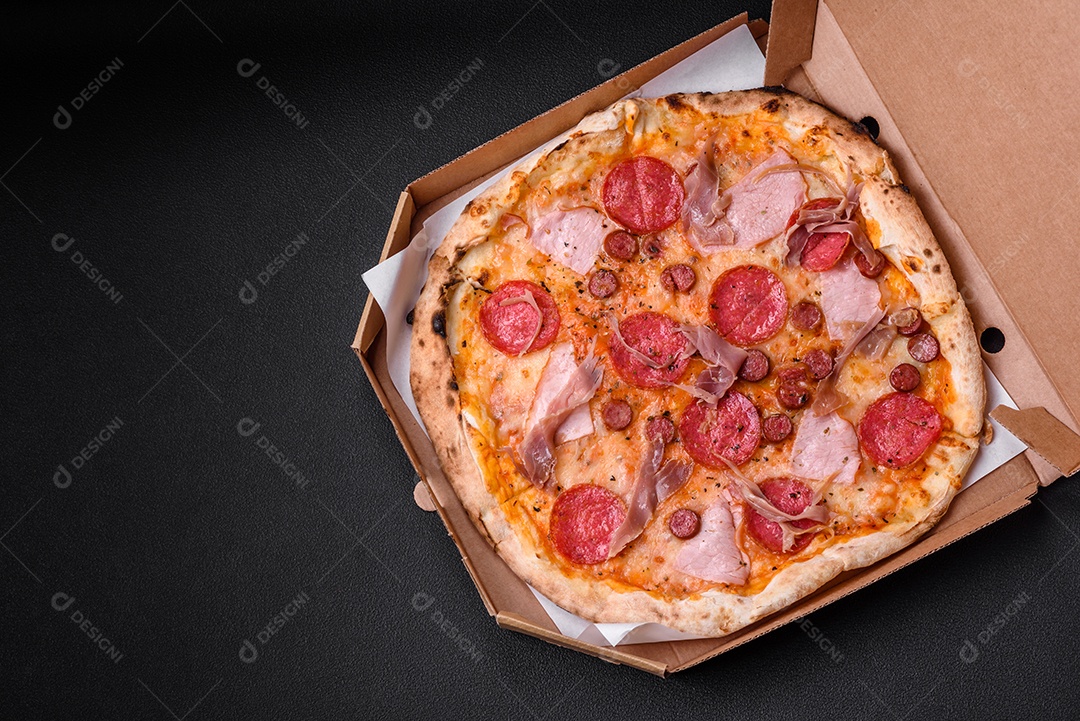 Deliciosa pizza assada em forno fresco com salame, carne, queijo, tomate, especiarias e ervas sobre um fundo escuro de concreto