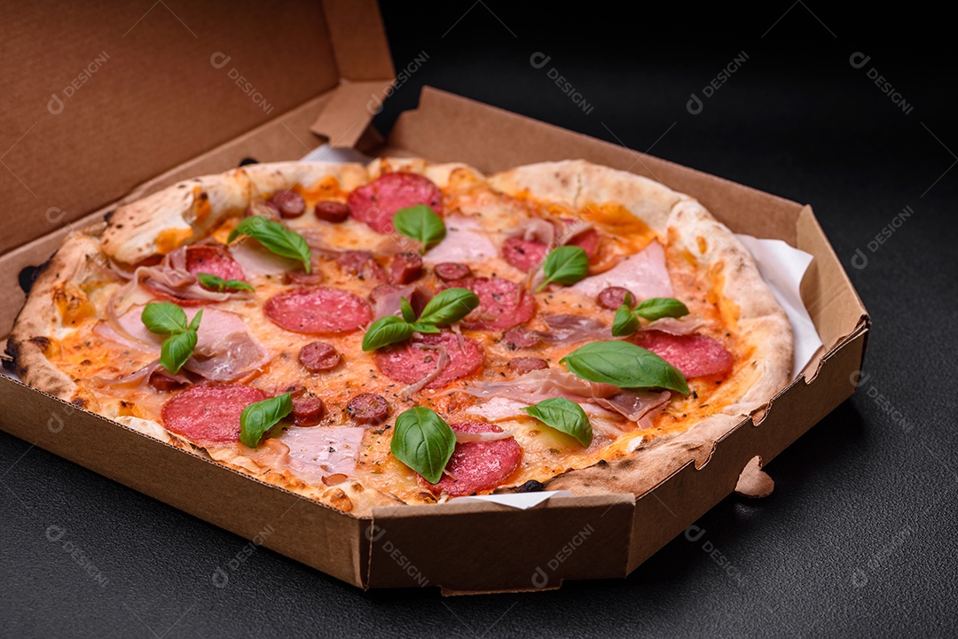 Deliciosa pizza assada em forno fresco com salame, carne, queijo, tomate, especiarias e ervas sobre um fundo escuro de concreto