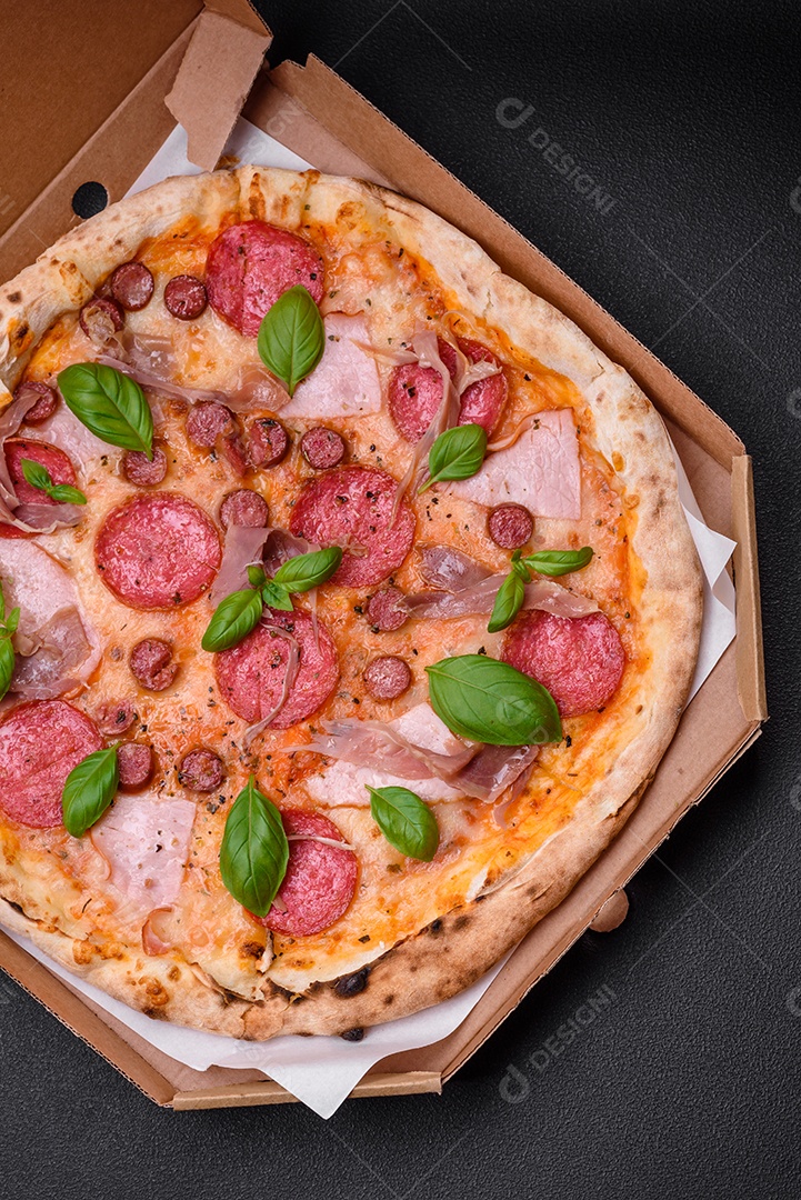 Deliciosa pizza assada em forno fresco com salame, carne, queijo, tomate, especiarias e ervas sobre um fundo escuro de concreto