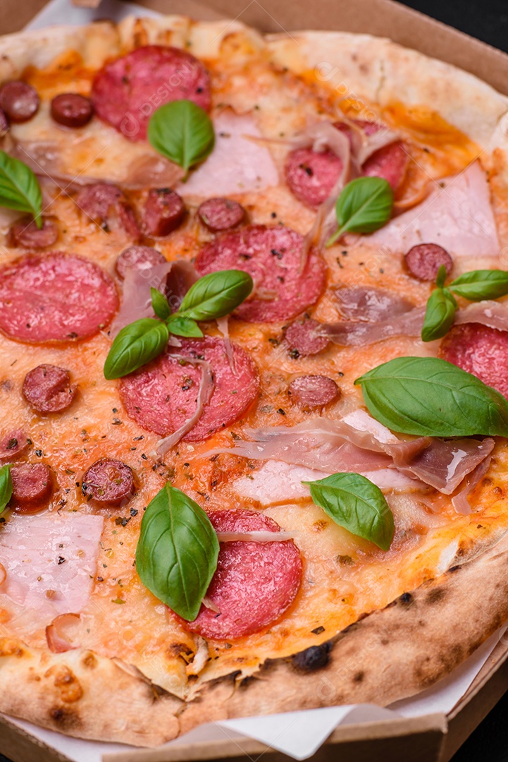 Deliciosa pizza assada em forno fresco com salame, carne, queijo, tomate, especiarias e ervas sobre um fundo escuro de concreto