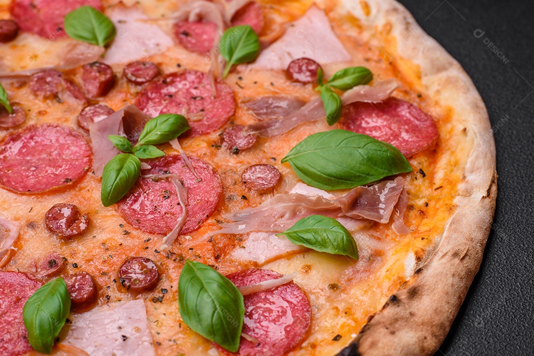 Deliciosa pizza assada em forno fresco com salame, carne, queijo, tomate, especiarias e ervas sobre um fundo escuro de concreto