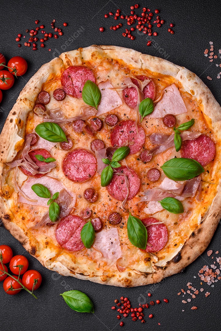 Deliciosa pizza assada em forno fresco com salame, carne, queijo, tomate, especiarias e ervas sobre um fundo escuro de concreto