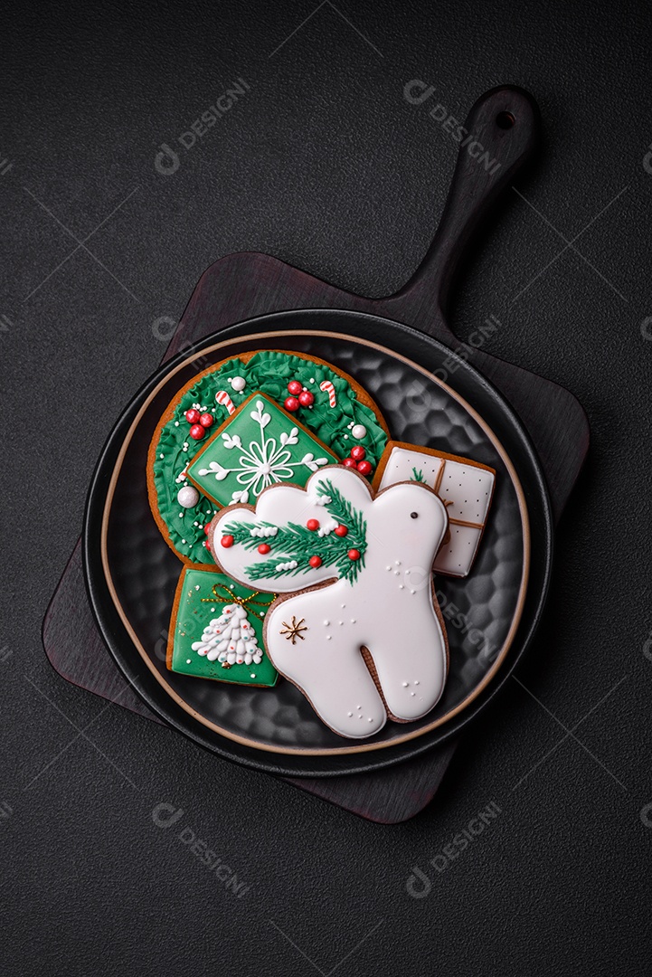 Lindos biscoitos de gengibre caseiros coloridos de Natal ou Ano Novo sobre um fundo escuro de concreto