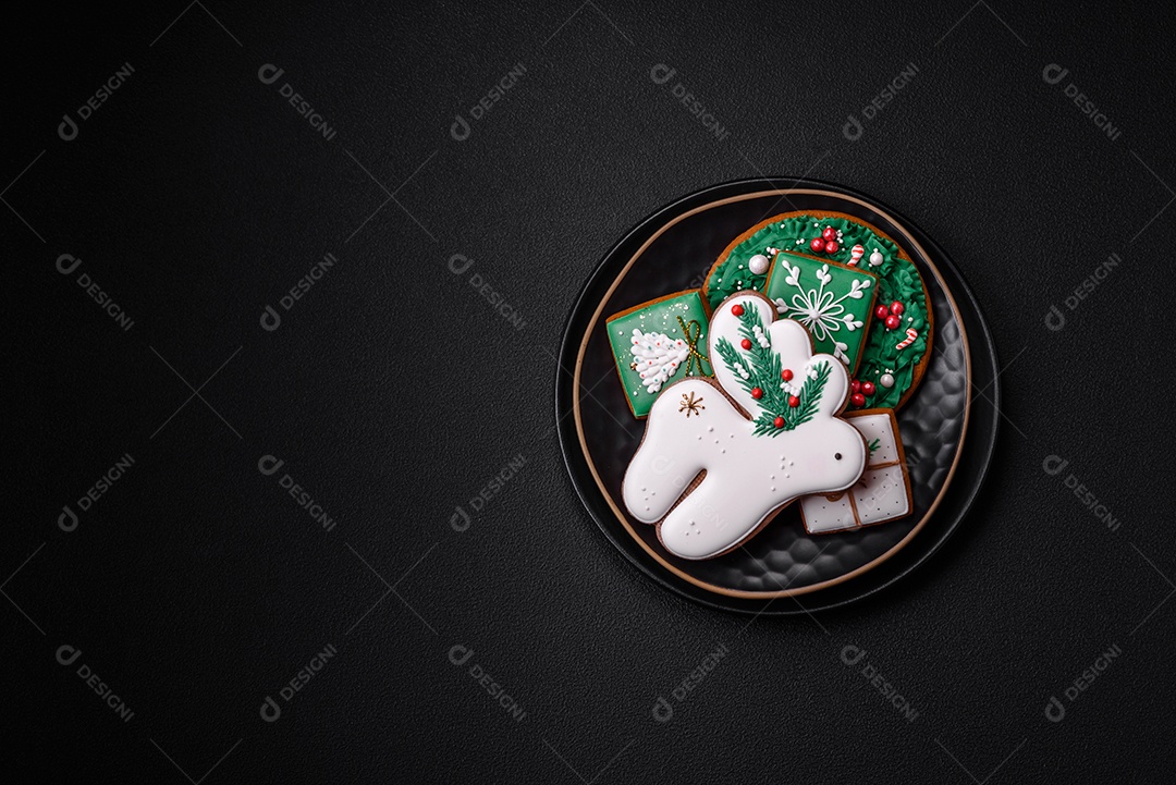 Lindos biscoitos de gengibre caseiros coloridos de Natal ou Ano Novo sobre um fundo escuro de concreto