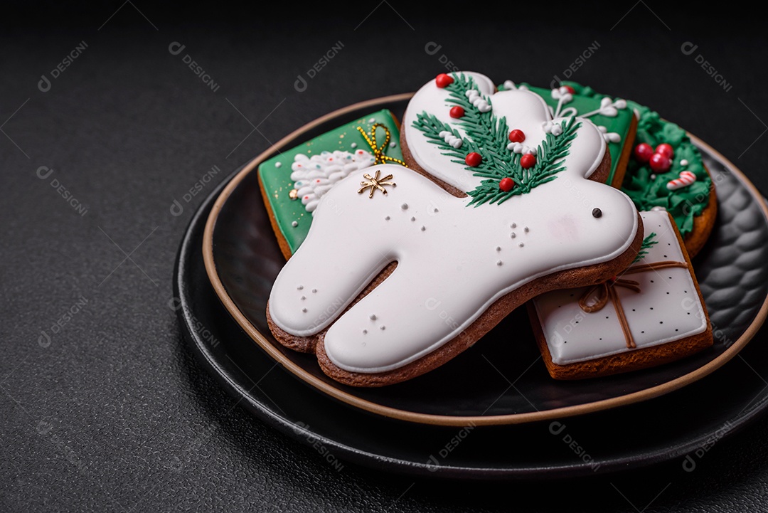 Lindos biscoitos de gengibre caseiros coloridos de Natal ou Ano Novo sobre um fundo escuro de concreto