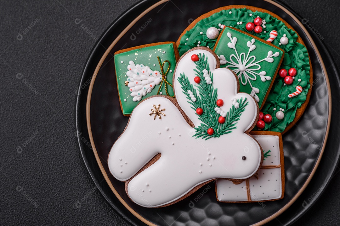 Lindos biscoitos de gengibre caseiros coloridos de Natal ou Ano Novo sobre um fundo escuro de concreto