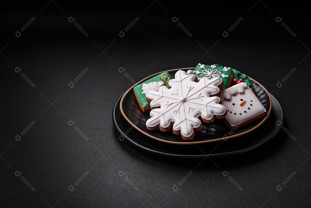 Lindos biscoitos de gengibre caseiros coloridos de Natal ou Ano Novo sobre um fundo escuro de concreto