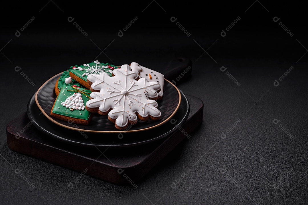 Lindos biscoitos de gengibre caseiros coloridos de Natal ou Ano Novo sobre um fundo escuro de concreto