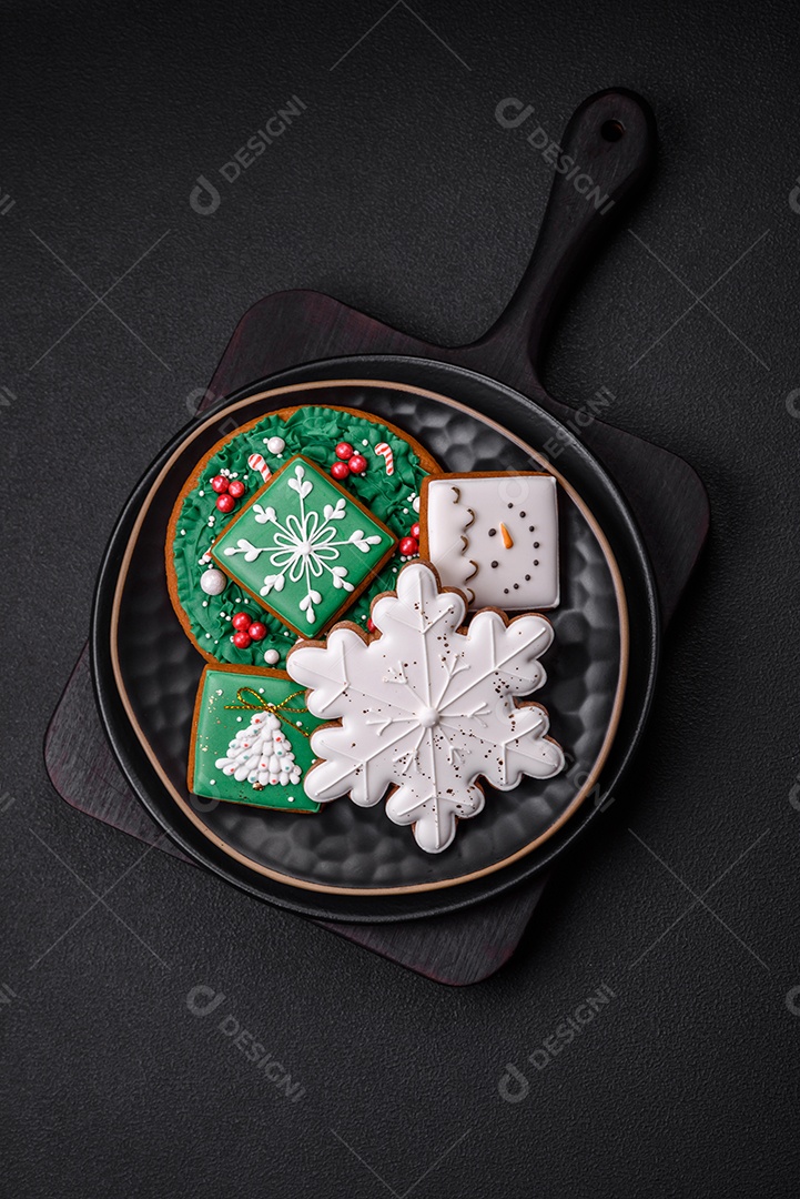 Lindos biscoitos de gengibre caseiros coloridos de Natal ou Ano Novo sobre um fundo escuro de concreto