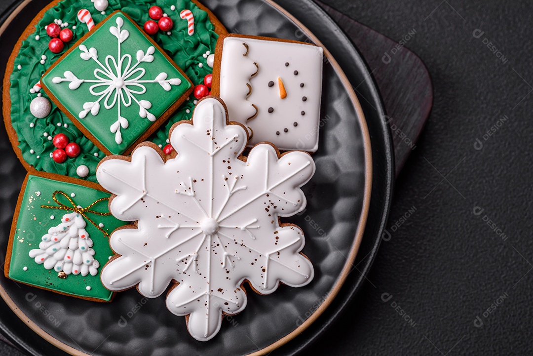 Lindos biscoitos de gengibre caseiros coloridos de Natal ou Ano Novo sobre um fundo escuro de concreto