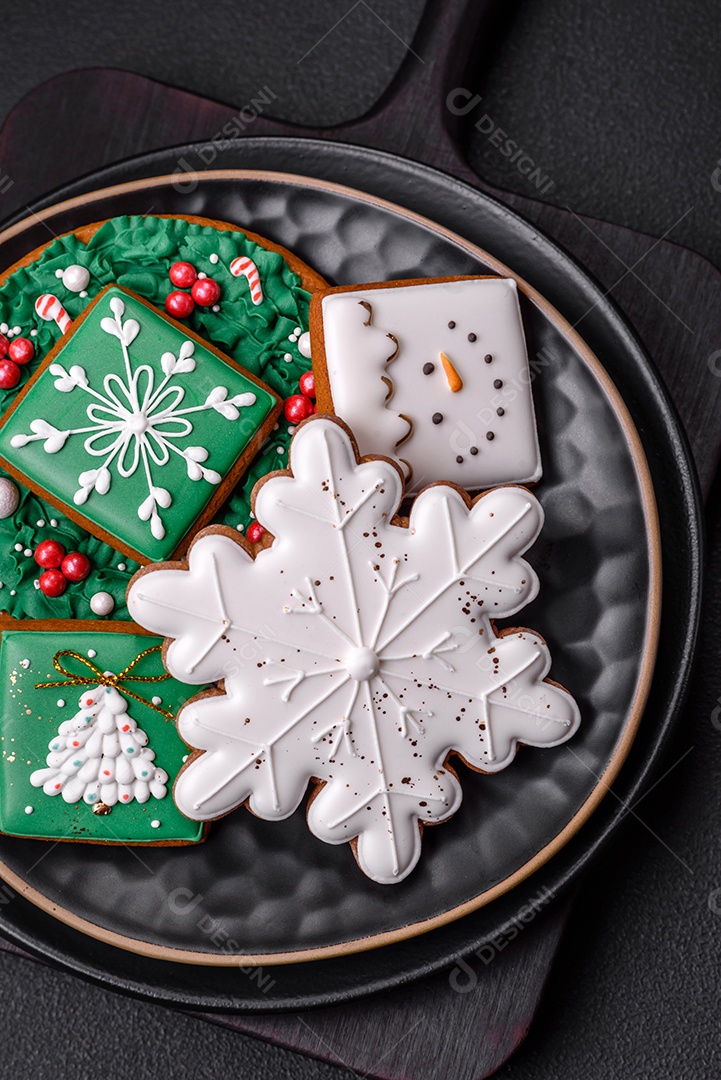 Lindos biscoitos de gengibre caseiros coloridos de Natal ou Ano Novo sobre um fundo escuro de concreto