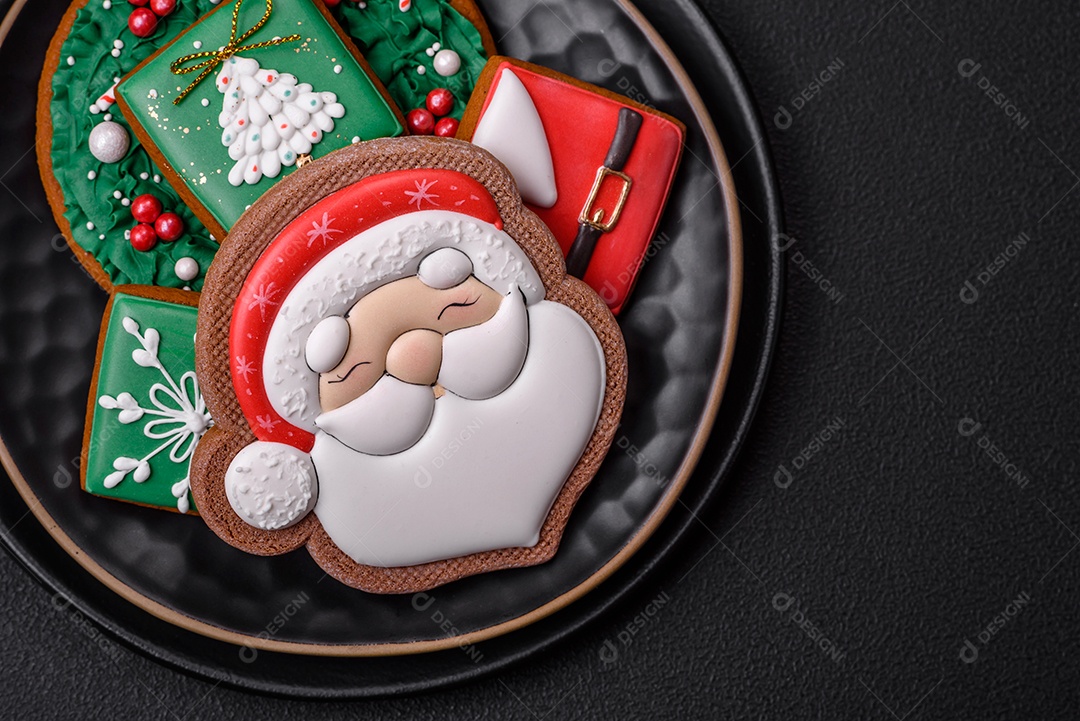 Lindos biscoitos de gengibre caseiros coloridos de Natal ou Ano Novo sobre um fundo escuro de concreto