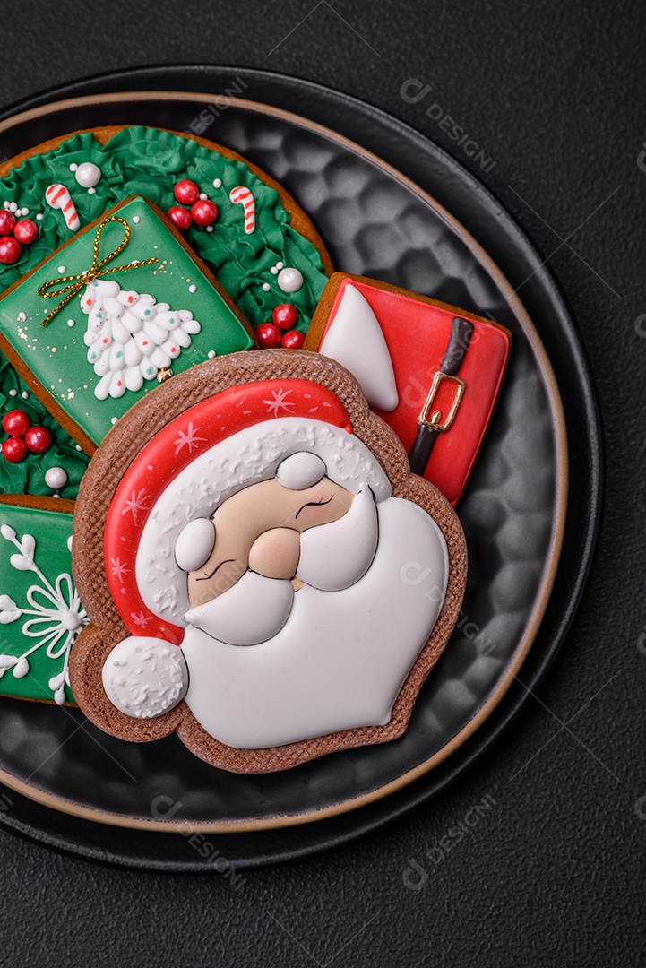 Lindos biscoitos de gengibre caseiros coloridos de Natal ou Ano Novo sobre um fundo escuro de concreto