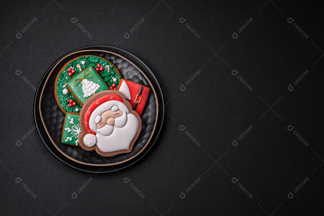 Lindos biscoitos de gengibre caseiros coloridos de Natal ou Ano Novo sobre um fundo escuro de concreto
