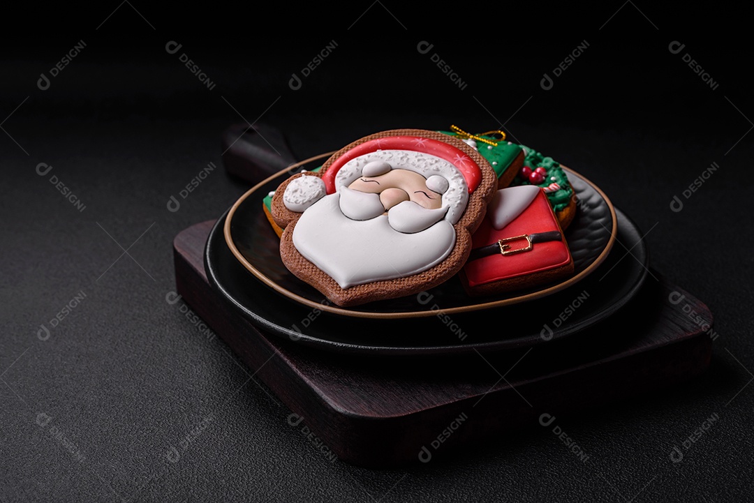 Lindos biscoitos de gengibre caseiros coloridos de Natal ou Ano Novo sobre um fundo escuro de concreto