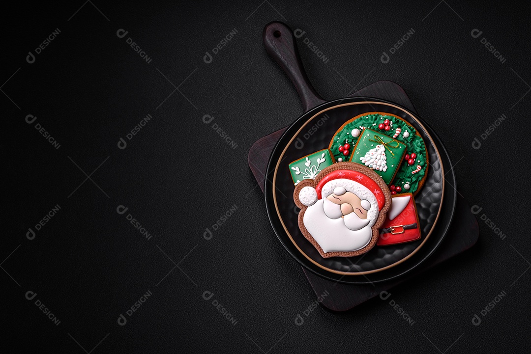 Lindos biscoitos de gengibre caseiros coloridos de Natal ou Ano Novo sobre um fundo escuro de concreto