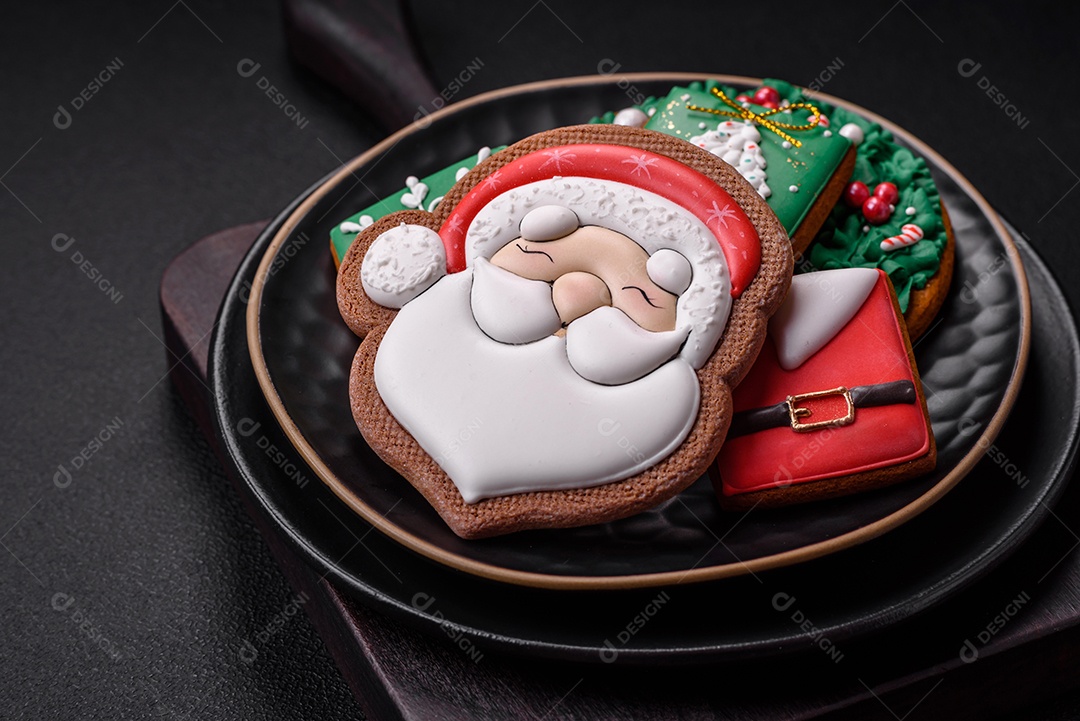 Lindos biscoitos de gengibre caseiros coloridos de Natal ou Ano Novo sobre um fundo escuro de concreto