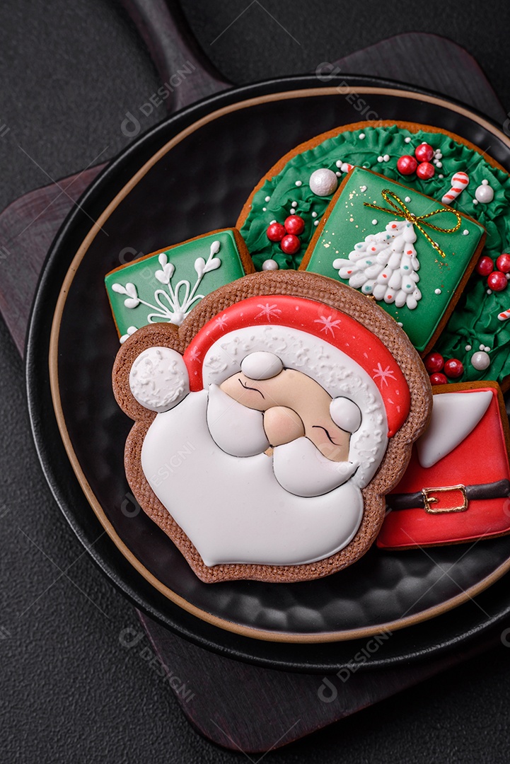 Lindos biscoitos de gengibre caseiros coloridos de Natal ou Ano Novo sobre um fundo escuro de concreto