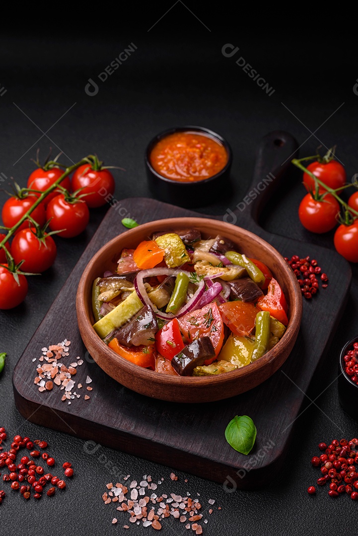 Deliciosa salada vegetariana fresca com tomate, feijão verde, berinjela, pimenta, sal, especiarias e ervas sobre um fundo escuro de concreto