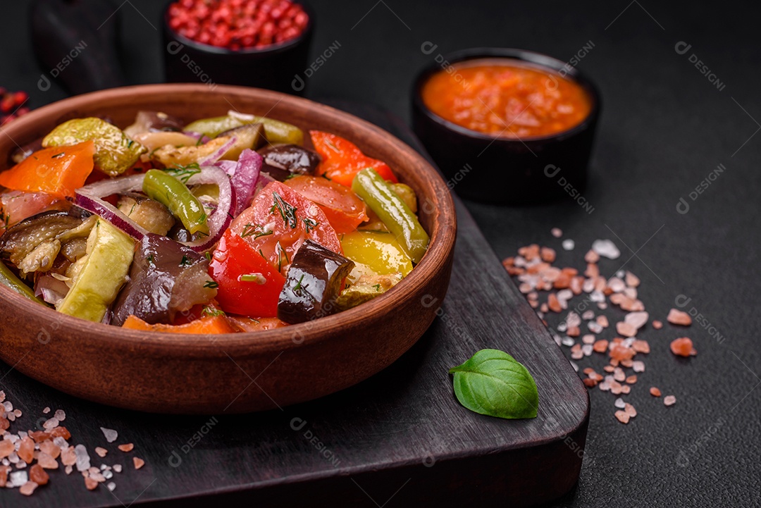 Deliciosa salada vegetariana fresca com tomate, feijão verde, berinjela, pimenta, sal, especiarias e ervas sobre um fundo escuro de concreto