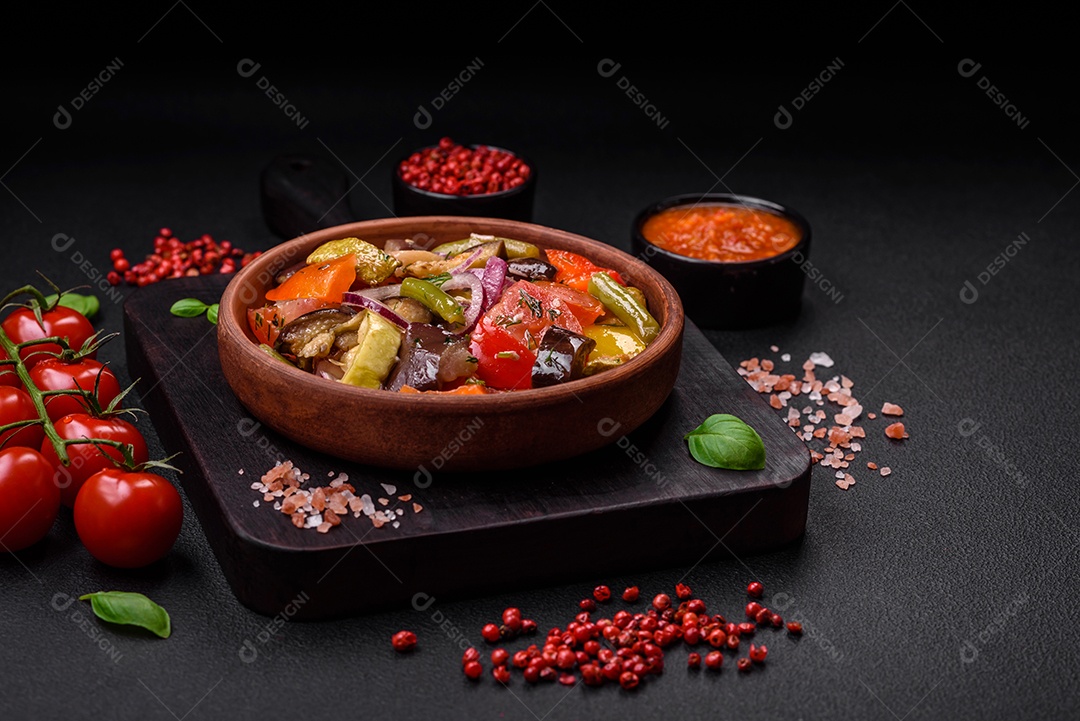 Deliciosa salada vegetariana fresca com tomate, feijão verde, berinjela, pimenta, sal, especiarias e ervas sobre um fundo escuro de concreto