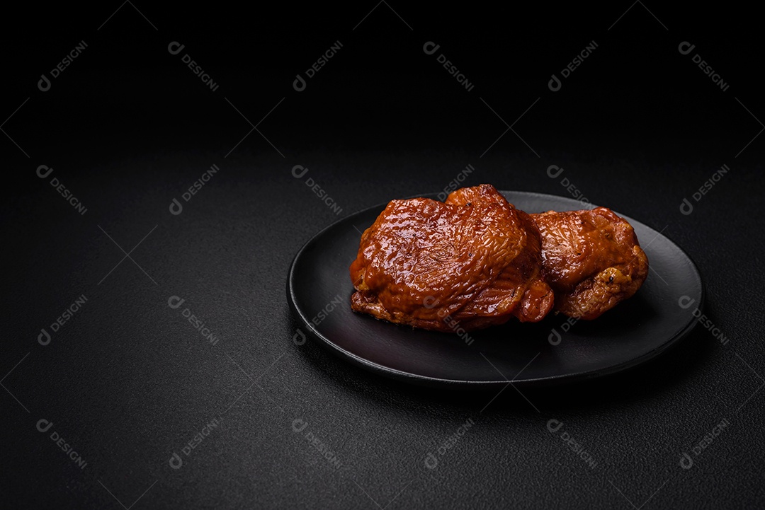 Deliciosas coxas de frango frito ou defumado grelhadas com especiarias e ervas sobre fundo escuro de concreto