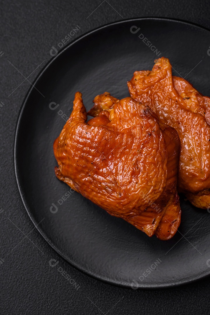 Deliciosas coxas de frango frito ou defumado grelhadas com especiarias e ervas sobre fundo escuro de concreto