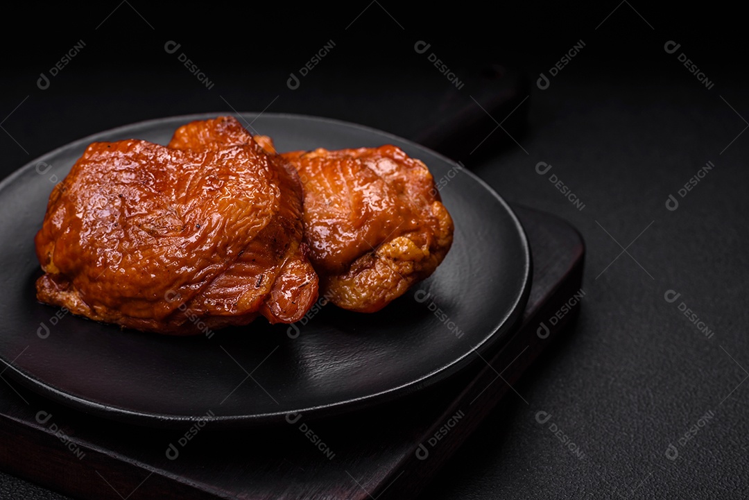 Deliciosas coxas de frango frito ou defumado grelhadas com especiarias e ervas sobre fundo escuro de concreto