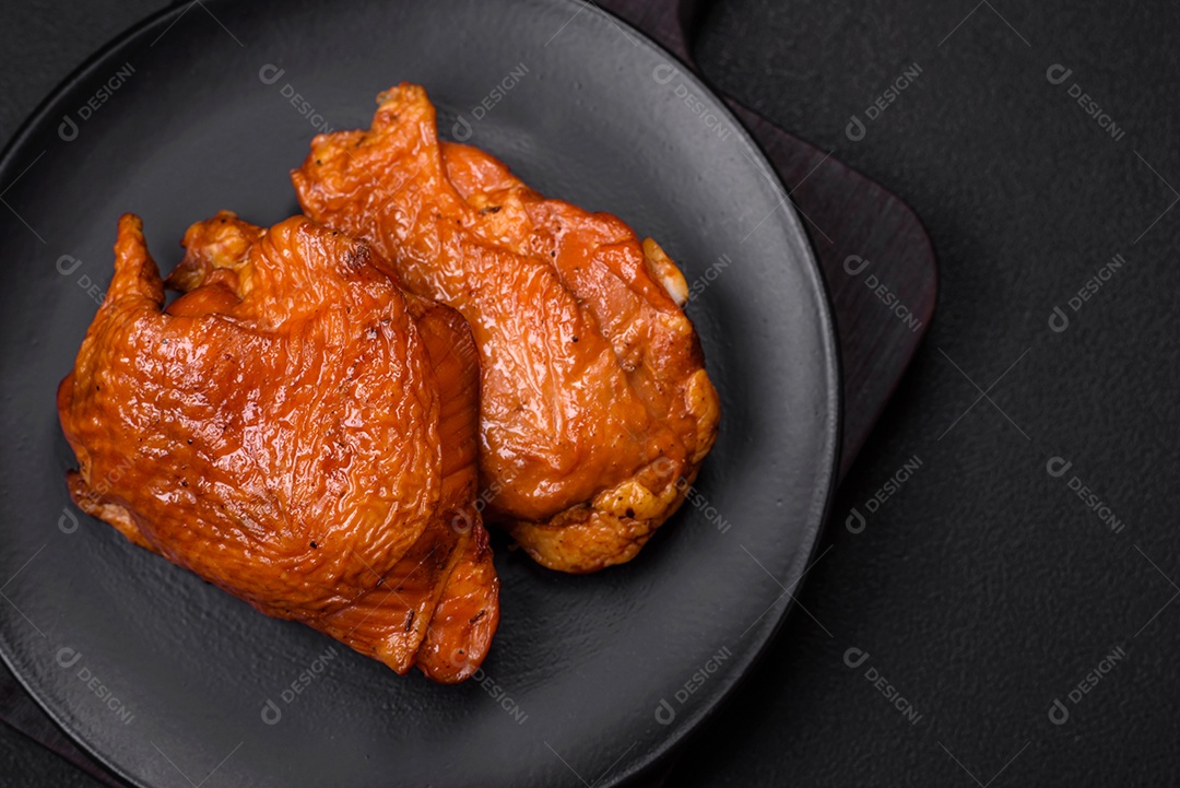 Deliciosas coxas de frango frito ou defumado grelhadas com especiarias e ervas sobre fundo escuro de concreto