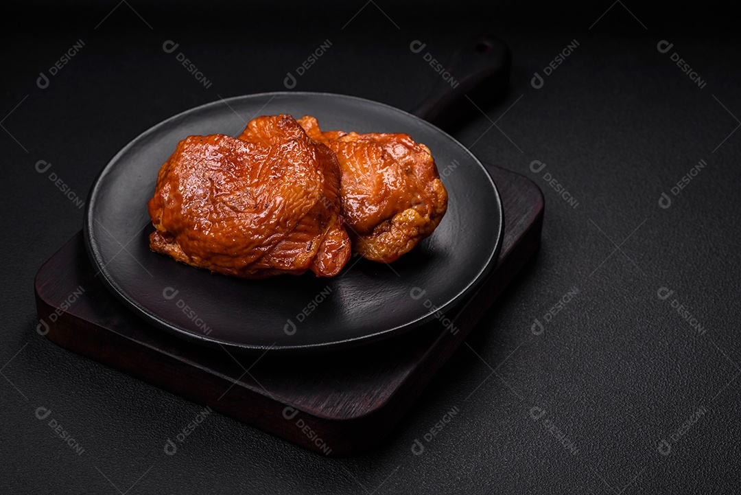 Deliciosas coxas de frango frito ou defumado grelhadas com especiarias e ervas sobre fundo escuro de concreto