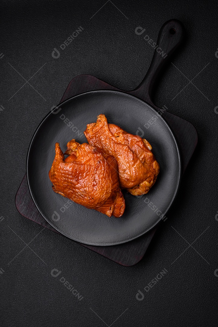 Deliciosas coxas de frango frito ou defumado grelhadas com especiarias e ervas sobre fundo escuro de concreto